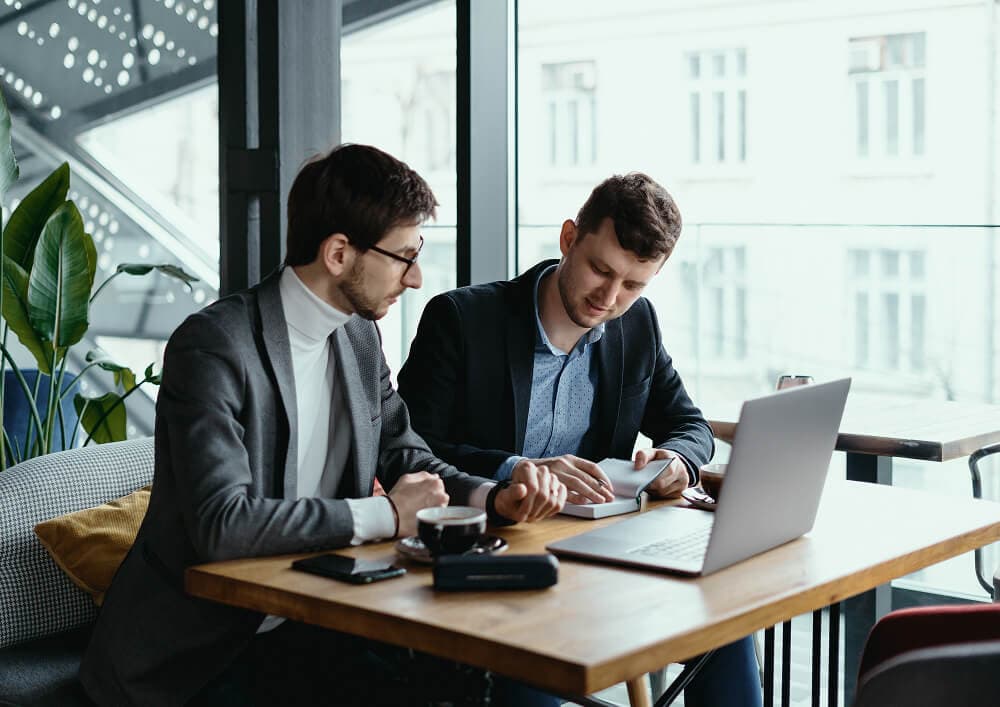 Two web developers collaborating on a laptop while planning a modern website project