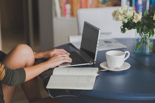 Designer sketching a website layout grid and wireframes on paper beside a laptop while planning page composition