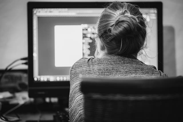 Network operations engineer reviewing traffic dashboards and alerts across multiple monitors while managing infrastructure